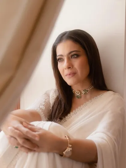 A serene portrait of Kajol. This shot highlights the delicate lace embroidery on the blouse and the timeless appeal of a simple white saree.