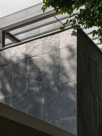 A close-up detail of the dark slate tile cladding used on the exterior. This durable and locally sourced Indian stone provides a rich texture that contrasts with the smooth white walls.