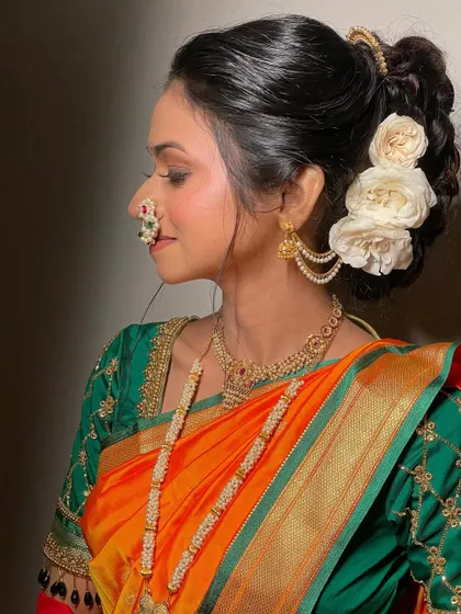 A profile view highlighting the bride's glow. The hairstyle is a beautiful bun adorned with fresh white roses, perfect for a classic Marathi wedding look.