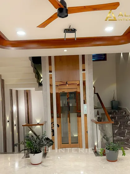 A view of the central staircase and elevator area, showcasing the blend of marble, wood, and glass. The thoughtful placement of indoor plants adds a touch of nature to the modern design.