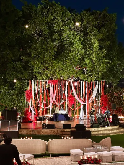 The amphitheater stage set for a Sangeet night, with a vibrant red and white ribbon backdrop, ready for music and dance performances.