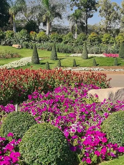 A beautiful view of a large park landscape, featuring manicured lawns, topiary shrubs, and colorful flower beds. This is the kind of peaceful scenery I love to create.