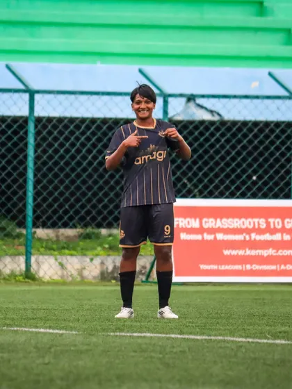 A player proudly points to her team's crest on her jersey, a sign of the pride and identity we foster in our young athletes.