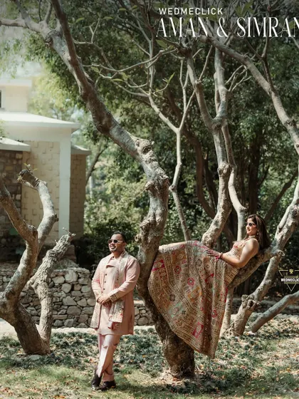 A creative and artistic portrait taken at a beautiful resort. Having her pose gracefully on the tree branch while he stands by adds a touch of whimsy and high fashion to their destination pre-wedding shoot.