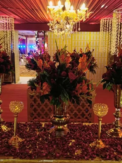 A grand entrance adorned with cascading florals, shimmering chandeliers, and rich red and gold details, setting the tone for an unforgettable evening.