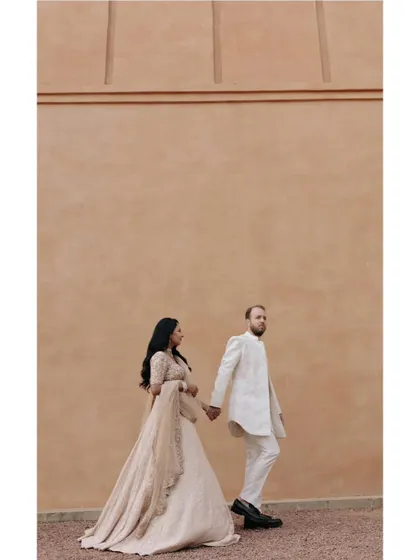A minimalist and powerful shot of Priyanka and Luke walking against a large, plain wall. This composition emphasizes their connection and the clean, modern aesthetic.