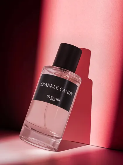 A minimalist yet striking shot of 'Sparkle Candy' perfume. The strong shadow and bold red background create a modern, high fashion look that is both simple and powerful.
