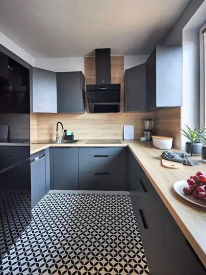 This U-shaped kitchen uses a dark grey and wood theme, complemented by a bold patterned floor tile. This design shows how to create a stylish and functional kitchen in a smaller footprint.