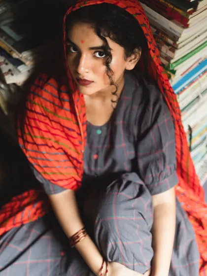 A high-angle shot from the bookshop editorial. The model's expressive look is enhanced by the subtle makeup and the single curl placed artfully on her forehead.