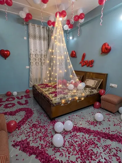 I transform ordinary bedrooms into romantic retreats. This setup features a sheer bed canopy with fairy lights, a floor scattered with rose petals, and balloon arrangements to create a cozy and intimate atmosphere.