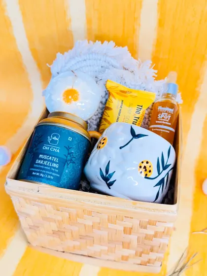 Tea, treats, and tender care, all she needs in one box. This is the inside of our "best-tea" hamper, filled with Muscatel Darjeeling tea, a daisy soap, a face serum, and a lovely mug.