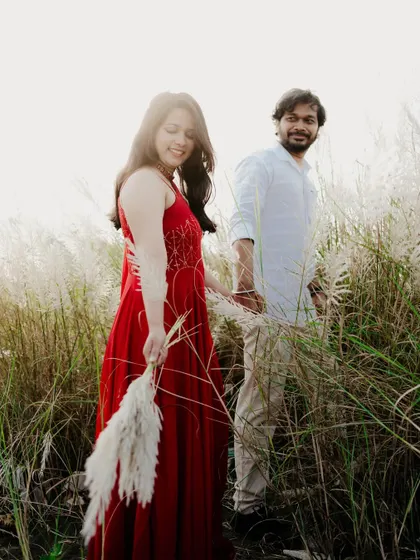 A candid shot of the couple walking through a field. The bride leading the groom creates a playful and interactive dynamic.