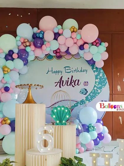 A closer view of the cake display area for the mermaid party, showing the pedestals, light-up number '6', and seashell prop.