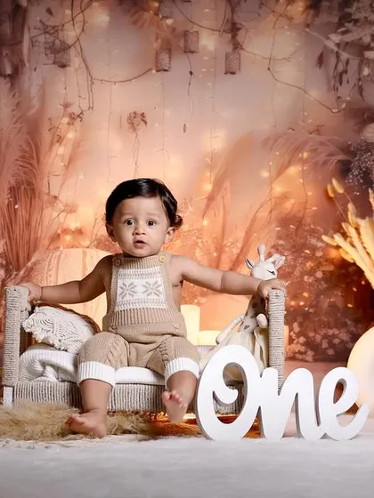 A beautiful boho-themed first birthday shoot. The neutral tones, pampas grass, and warm candlelight create a trendy and timeless portrait.
