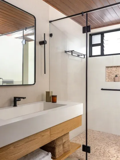A bright and airy bathroom with a wood-paneled ceiling and a floating oak vanity. The design feels clean, modern, and connected to nature.