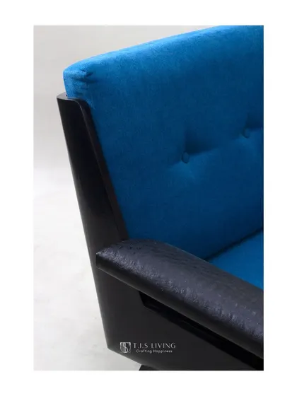 A detail shot of the lounge chair, showing the contrast between the smooth black frame, the textured leather armrest, and the soft blue fabric.