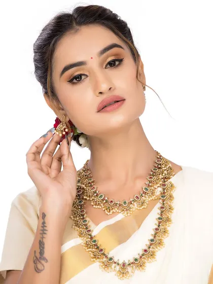 This image highlights the detailed craftsmanship of another traditional necklace set, with the model's pose drawing attention to the earrings.
