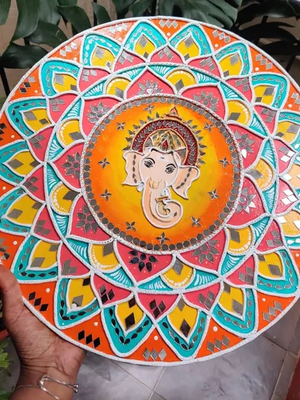 A full view of the 16-inch Ganesha Lippan art on a wooden board. The intricate mandala pattern surrounding Ganesha is filled with bright colors and detailed mirror work.