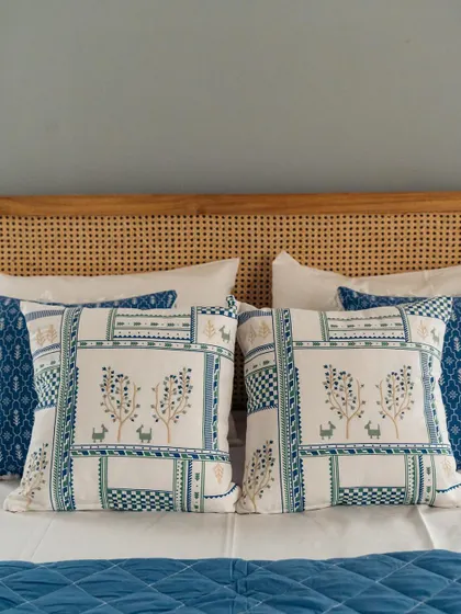 A close-up of the bed from our blue-themed room makeover. The headboard is adorned with our 'Forest Patch' cushion covers, which feature a charming patchwork of prints and textures.
