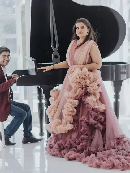 A playful and elegant shot at a grand piano in a white studio. The bride's magnificent ruffled gown is the centerpiece of this beautiful composition.