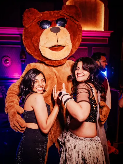 Guests dance with a giant teddy bear mascot, one of the many surprise entertainment elements at the 'Cirque of Love' themed party.