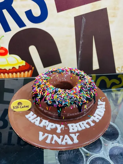 A fun 500g donut-shaped cake covered in chocolate glaze and rainbow sprinkles.