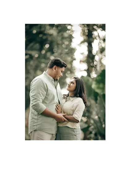 A classic, romantic portrait of a couple looking into each other's eyes, surrounded by soft, out-of-focus greenery.