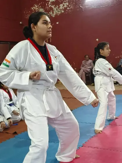 Students holding a ready stance during a Taekwondo class. This fundamental pose is the foundation for both blocking and striking.