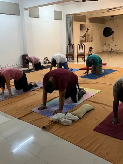 A full class practices a sequence from Surya Kriya together, their movements synchronized in a wave of energy.