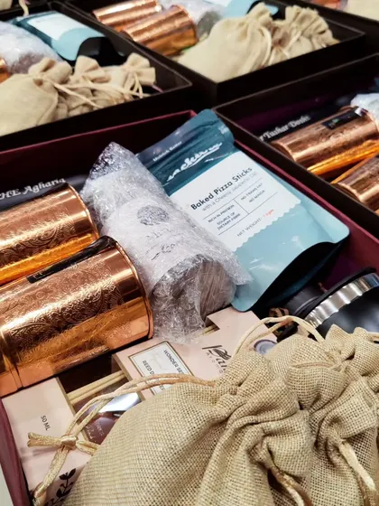 A closer look at the contents of a bulk hamper order. Each box is filled with copper glasses, snacks, and other personalized items.