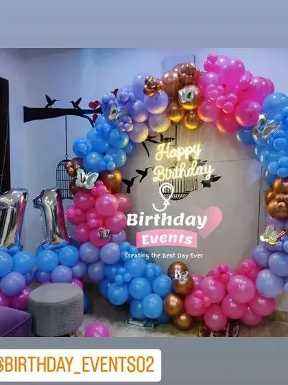 A playful and colorful setup for an 11th birthday, using blue, pink, and purple balloons with butterfly and bird wall decals in the background.