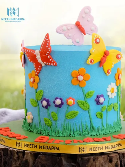 A close-up of the vibrant butterfly garden cake, showing the detailed fondant flowers and fluttering butterflies.