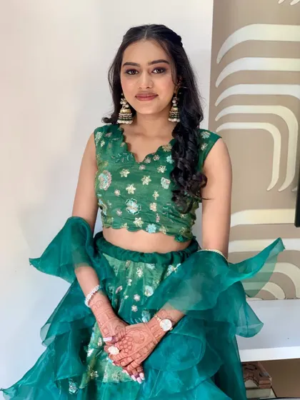 A full view of bridesmaid Bhakti's look. The green lehenga with ruffle details is fun and festive, and her makeup is fresh and glowing.