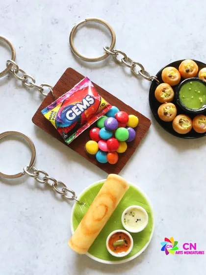 A set of three food keychains: dosa, pani puri, and Gems chocolates.