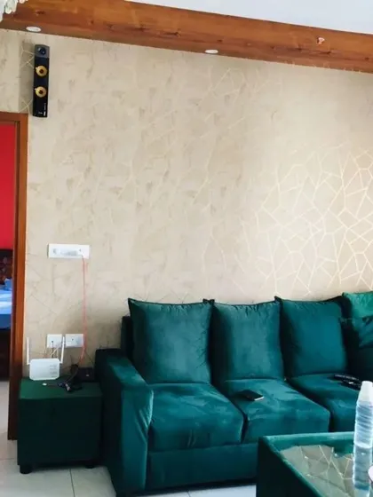 This living room features a subtle, textured wallpaper with a light geometric pattern. It adds interest and warmth to the wall without competing with the bold green sofa.
