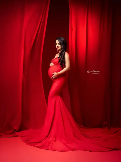 A full-length view of this beautiful red gown, showing its graceful train. The pose is confident and serene, capturing the power of motherhood.