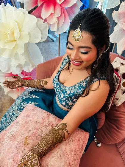 A beautiful bride surrounded by giant paper flowers, her portrait mehndi on display.