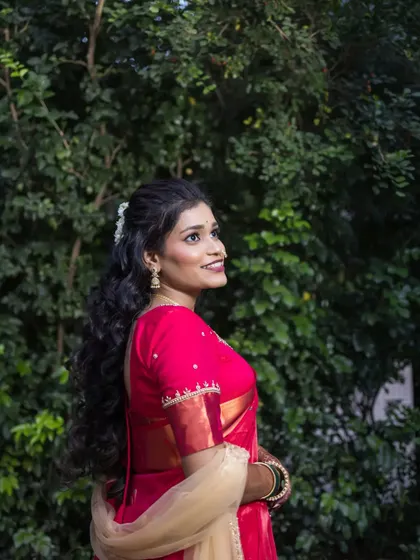 A profile shot of the bride against a natural green background, highlighting her beautiful hair and joyful expression.