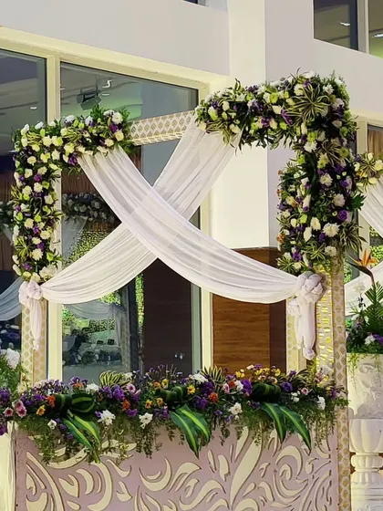 An elegant decor element featuring white fabric crisscrossed over a floral arrangement. The mix of white, purple, and green creates a fresh and sophisticated look.