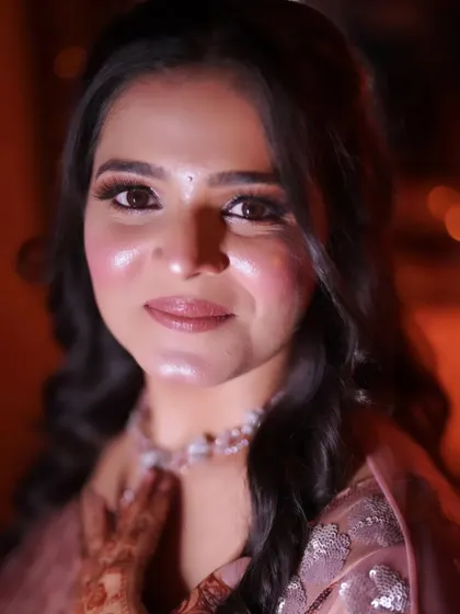 A close-up portrait showing off the glowing skin and soft pink tones of this engagement makeup look.