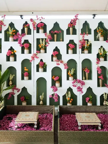 A closer look at the haldi backdrop, where a wall of jharoka-style niches is filled with small floral arrangements, creating a beautiful texture.