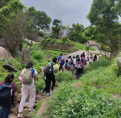 A group of mothers and children hiking together on a rocky, green trail. Our guides lead the way, ensuring a safe and enjoyable journey for everyone.