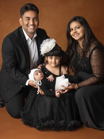 A beautiful first family portrait. The parents and big sister gaze lovingly at the newest member of their family, a peacefully sleeping newborn.