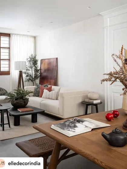 A view from the dining area into the living space, showing the cohesive design language. The open-plan layout is unified by a neutral palette and the consistent use of warm wood and natural textures.