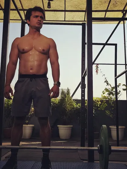 A behind the scenes shot from a fitness photoshoot. Standing ready in front of the barbell, embodying the strength and focus that training cultivates.