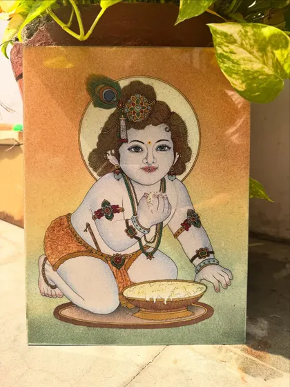 This painting shows Lord Krishna as a child, or Bal Gopal, enjoying a bowl of butter. I use fine gemstone powder and crystals to give the piece a gentle sparkle that captures his playful and beloved nature.