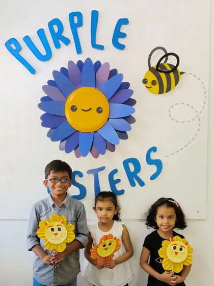 Our little Asters stand by the Purple Asters logo with their paper lion crafts. These moments of pride and accomplishment are what our camp is all about.