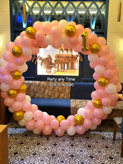 A simple circular balloon arch in pastel pink and white with gold accents.