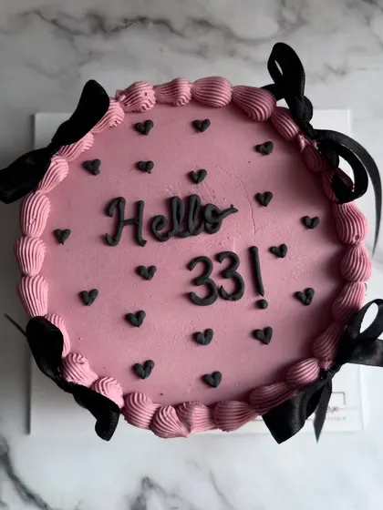 A chic and modern take on the vintage style. This "Hello 33" cake features a dusty pink base, black heart details, and is adorned with elegant black satin bows.