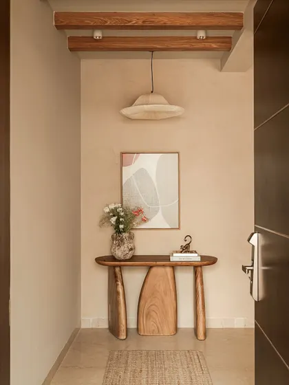 The experience of a home begins the moment you enter. I designed this entryway with a handcrafted sculptural wood console and exposed ceiling beams to create a warm, welcoming transition that celebrates natural materials and artisanal skill.